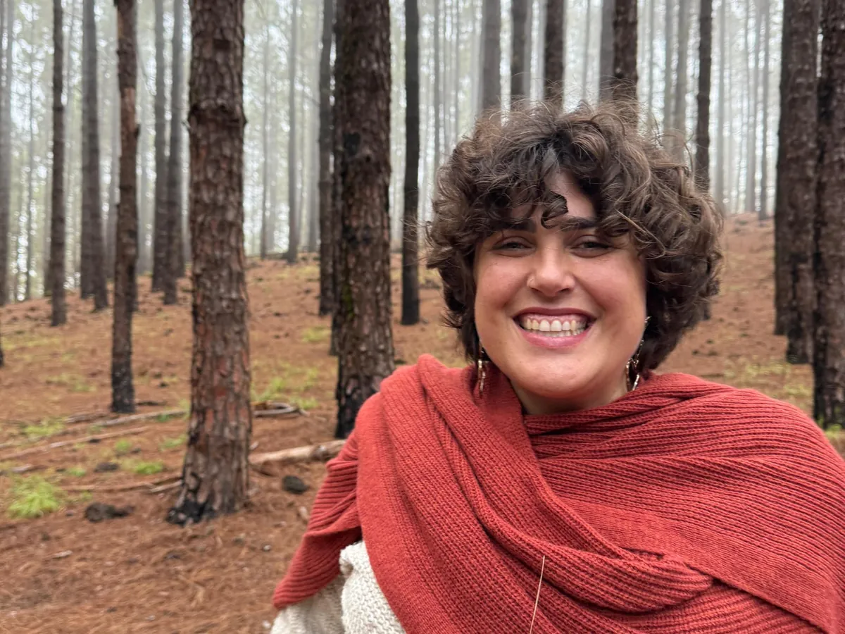 Lara Lapuente sonriendo en un bosque de pinos